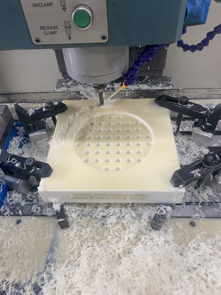 CNC mill drilling a precision hole pattern into a workpiece with coolant spraying