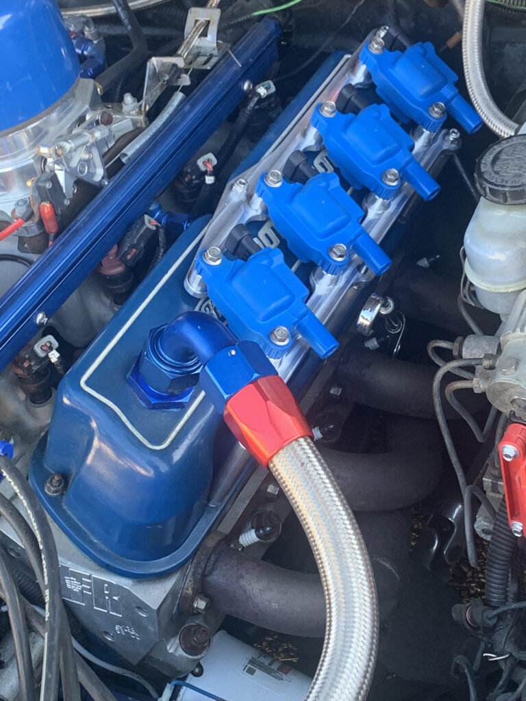 Custom blue anodized coil pack mounting bracket installed on an engine