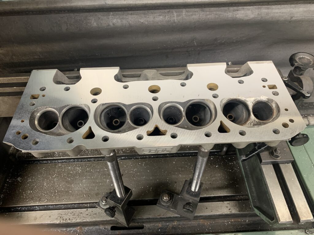Close-up of a freshly machined cylinder head showing valve seats and combustion chambers
